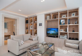 Multiple modernly designed shelfs with books and a smart tv in the living room.