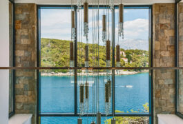 The luxury chandelier in front of a large window which looks directly on the sea.