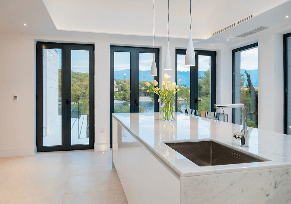 Modern kitchen area with 4 windows that provide a view on the sea.