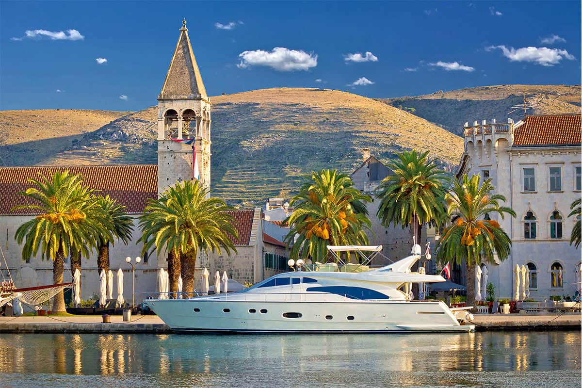 The white yacht anchored in the historic town with a view on the mountain.