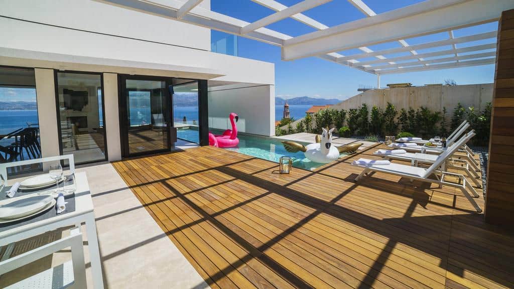 The large terrace of the luxury beach house with a swimming pool and two sunbeds.