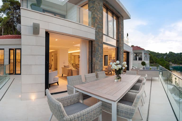 The image of alfresco dining area on the terrace of the luxury villa built in white stone.