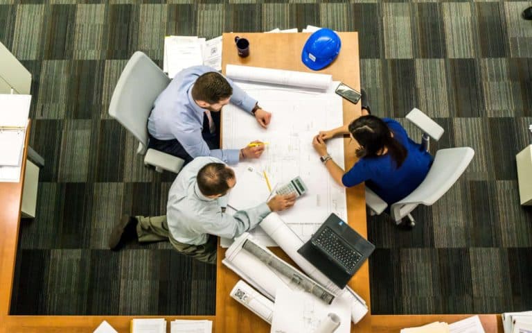 Three architects discussing over a blueprint.