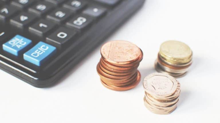 A coin change and a pocket calculator on a white table.