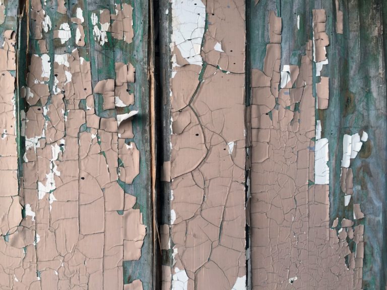 Aan outdated green and brown paint falls off the wooden doors.