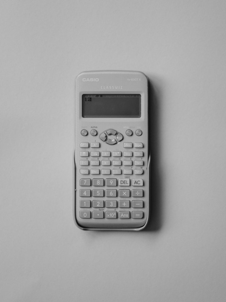 The white Casio calculator on the plain white surface.