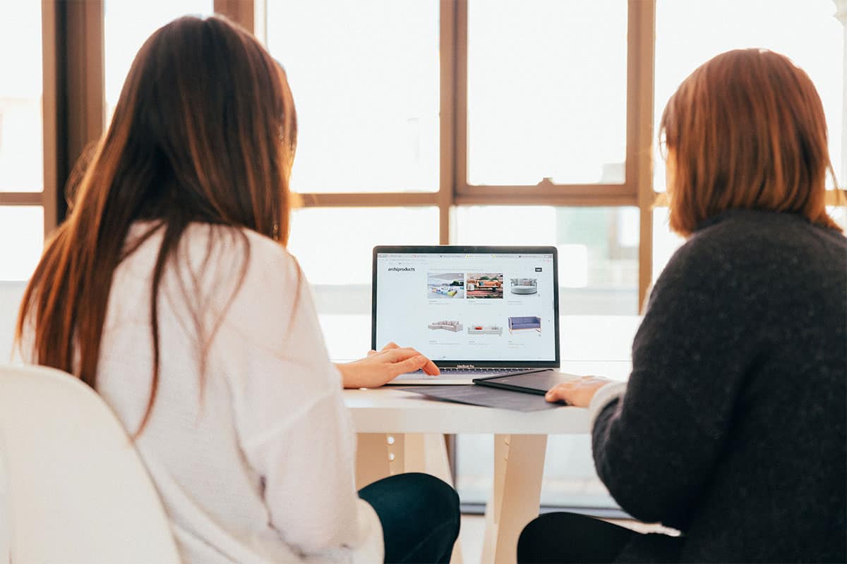 Two women looking on the laptop.